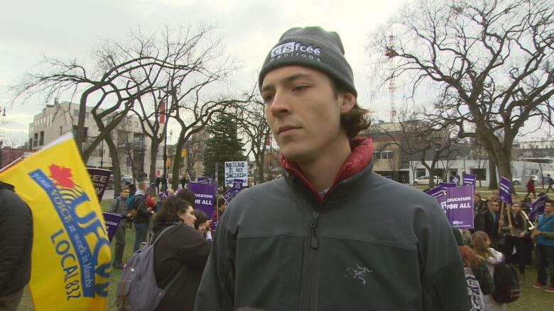 A person in a toque stands outside at a rally.