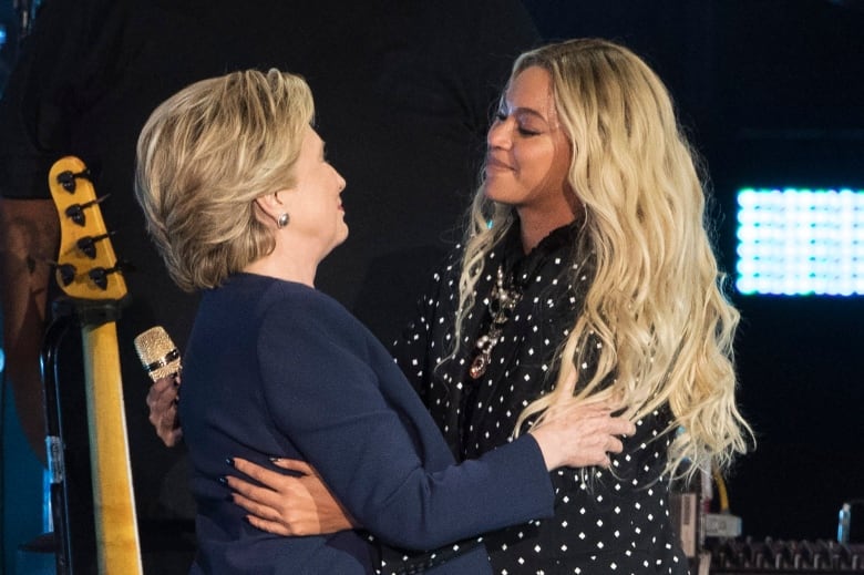 Two women embrace on a stage