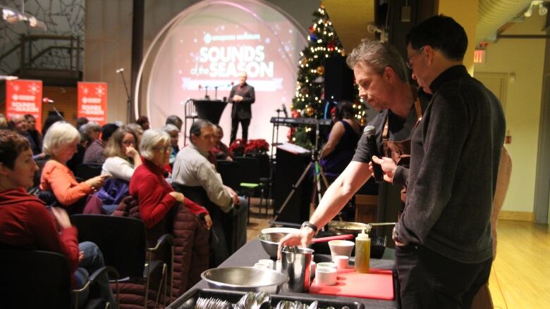 Male chef makes a dish as he's interviewed in front of an audience