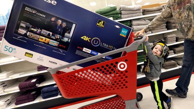 In this Friday, Nov. 25, 2016, file photo, Hunter Harvey helps his dad, C.J., wheel a big screen TV at Target, in Wilmington, Mass. 