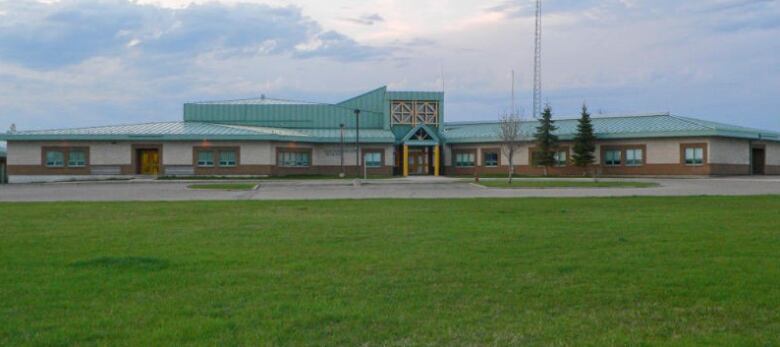 A photo of the outside of a school in front of green grass on a blue-sky day. 