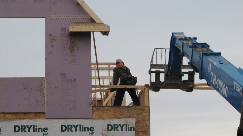 A working on the edge of un upper floor of a new home under construction.  