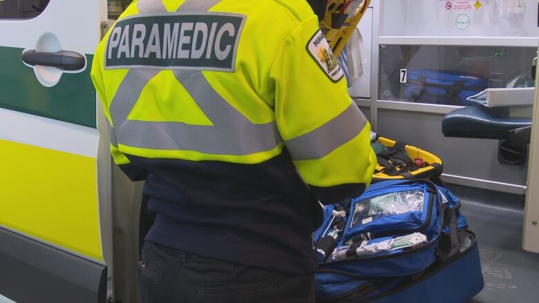 A woman on a paramedic outfit looking at blue bag inside an ambulance.