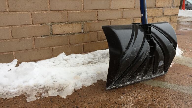 A snow shovel leaning against a wall.