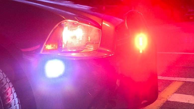 Blue and red flashing lights are seen on the front-end of a police cruiser at night.