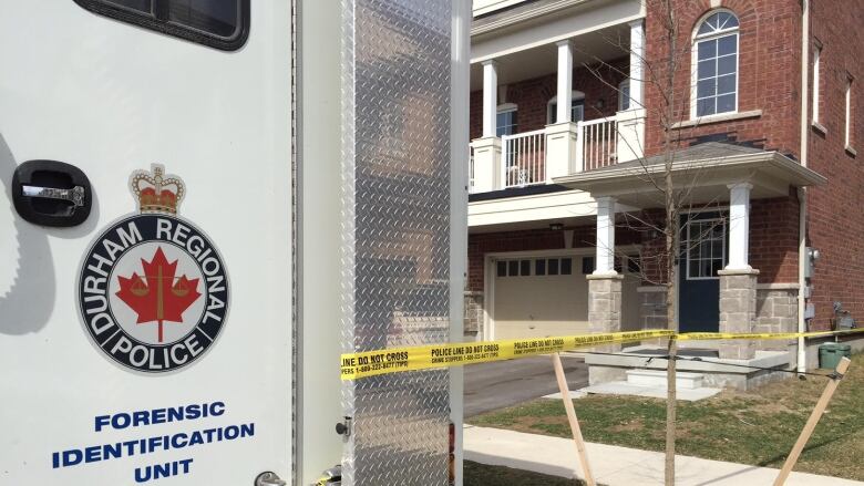 A police van and police tape in front of a home.