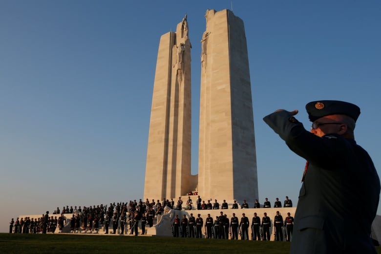 A soldier salutes a monument at dusk.