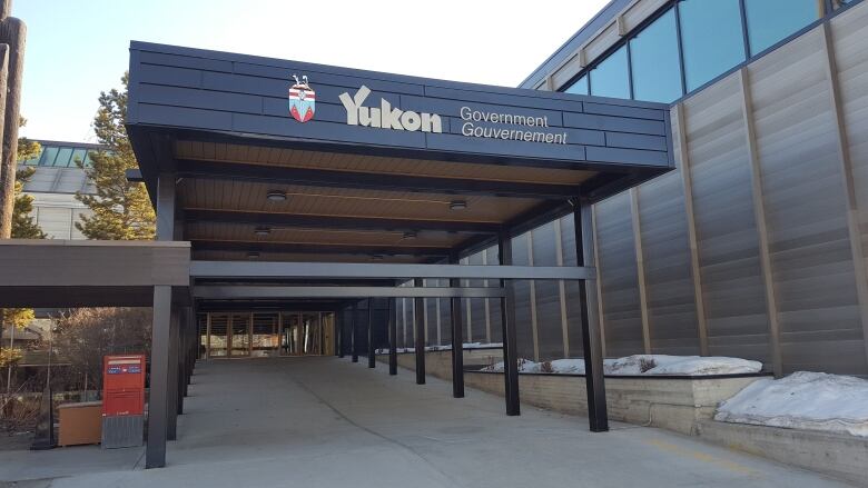 A covered walkway leading to glass doors. 