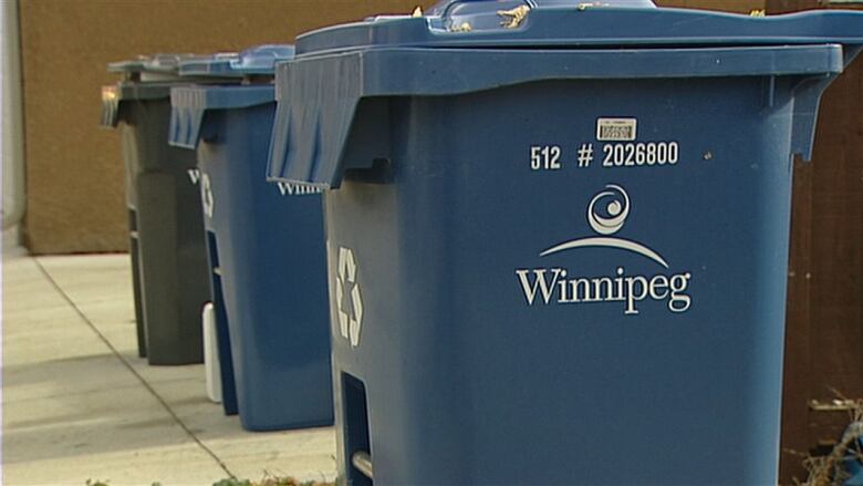 Blue wheeled bins with the City of Winnipeg logo on their side.