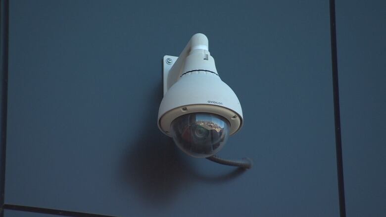 A security camera attached to a blue wall.