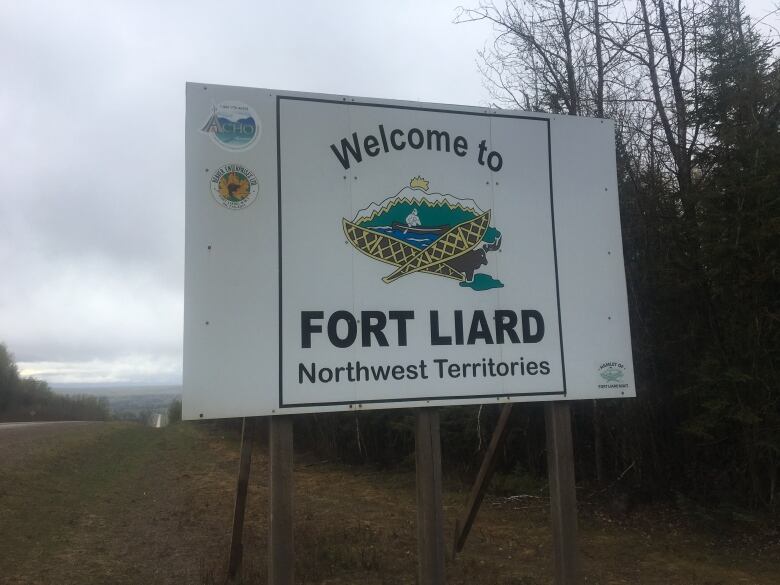 A white sign along a highway on a grey day. 