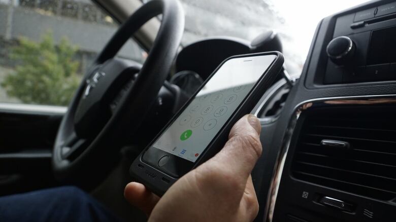 Persons holds a phone while driving.