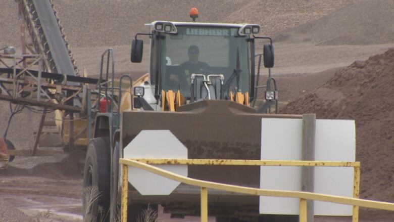 a frontloader surrounded by rocks and mud.