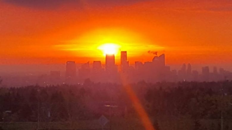 Calgary's skyline is silhouetted in red. 