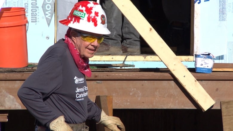 Jimmy Carter in hard hat, bandana and gloves, while on a Habitat for Humanity site.