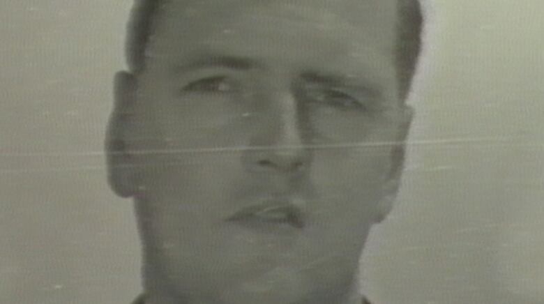 A black and white headshot of a young man with short hair.