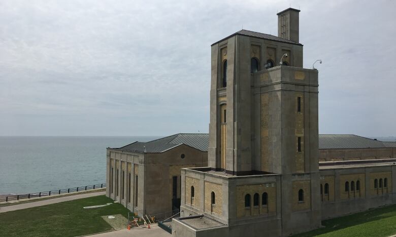 Daytime photo of the R.C. Harris Water Treatment Plant in Toronto. Built in the art-deco style, it looms over Lake Ontario and is surrounded by lush green lawns.