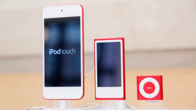 Close up of a red iPod Touch, a red iPod Nano and a red iPod Shuffle on display in a store.