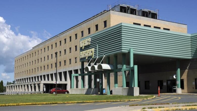 A large beige and grey building with a green entryway