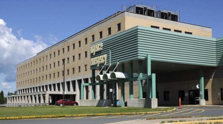 A large beige and grey building with a green entryway