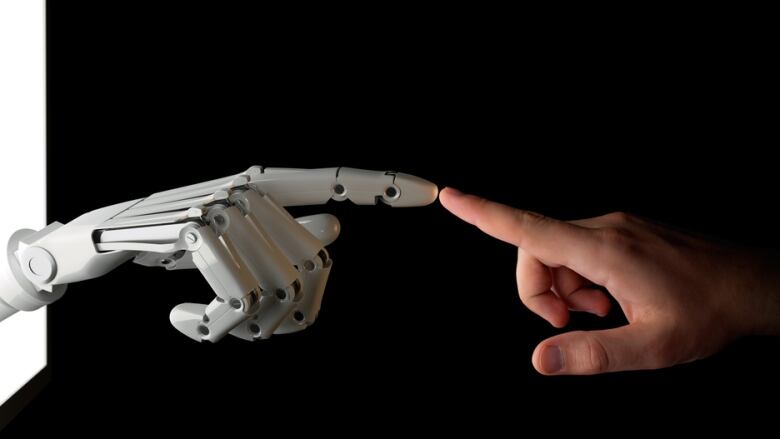 A robot hand and a human hand touch fingers.