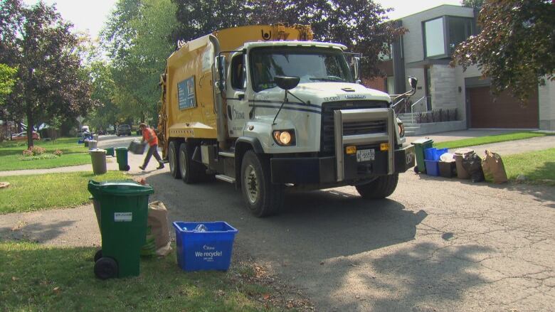 A garbage truck in front of a lawn.