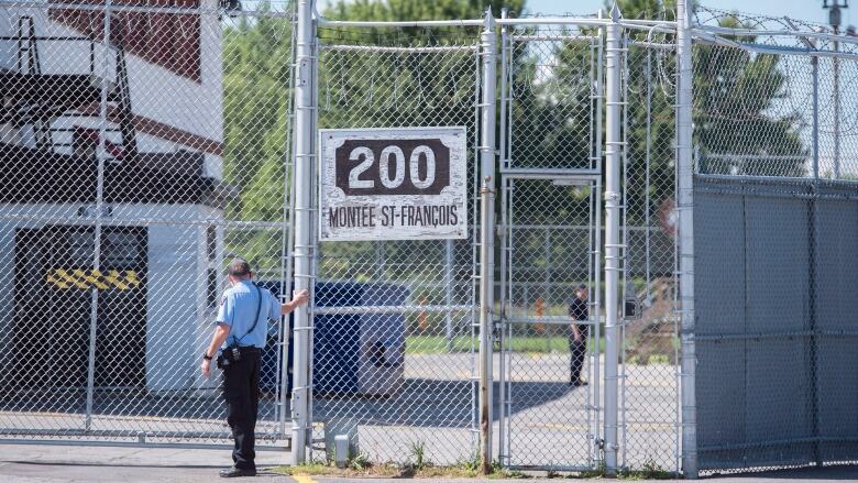 A guard stands outside gates of an immigration holding centre.