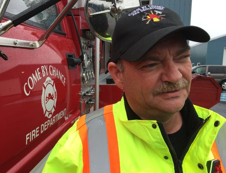 a portrait style photo of the fire chief in come by chance, with a fire truck in the background.