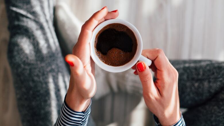 Hands hold a mug of coffee.