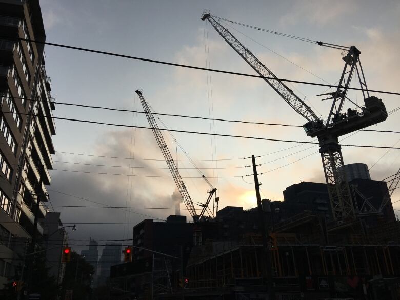 A silhouette of a crane at a construction site.