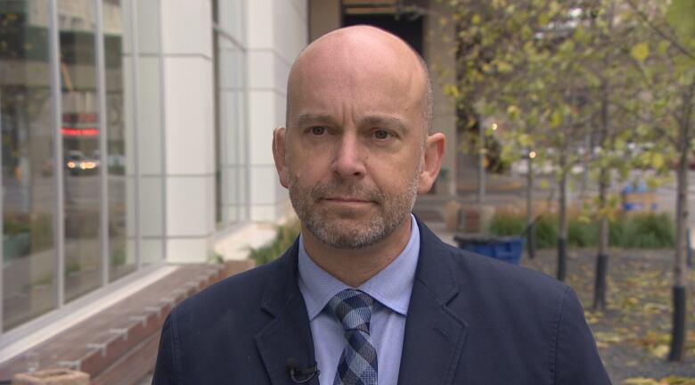 A man in a dark suit and tie speaks with a reporter.