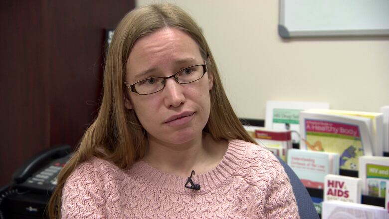 A woman wearing glasses looks serious in an office.