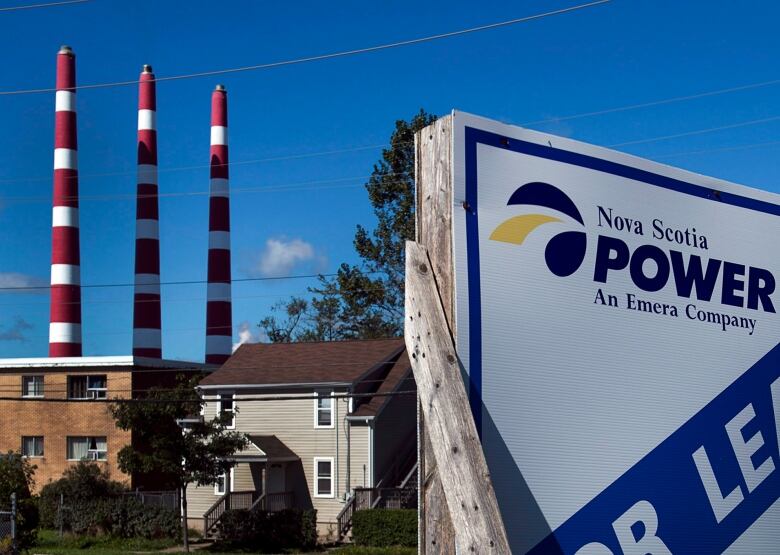 A Nova Scotia Power sign is shown in the foreground. In background are houses and the Tufts Cove generating station stacks.