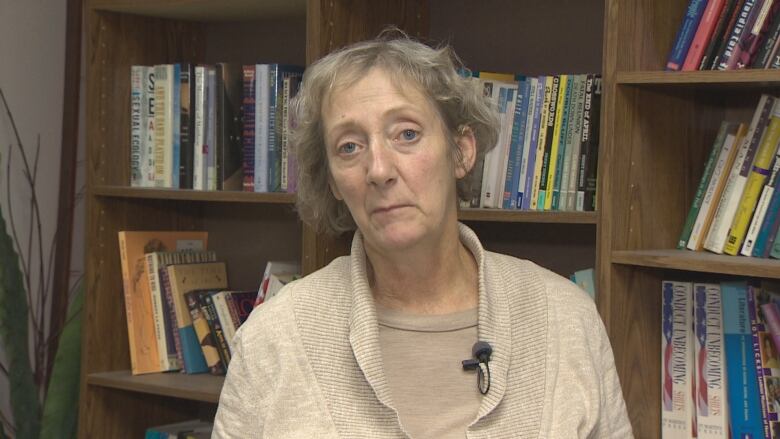 A woman in front of a book case. 