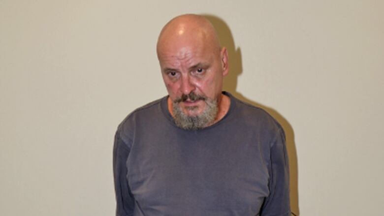 A man in a blue shirt against a pale-coloured wall.