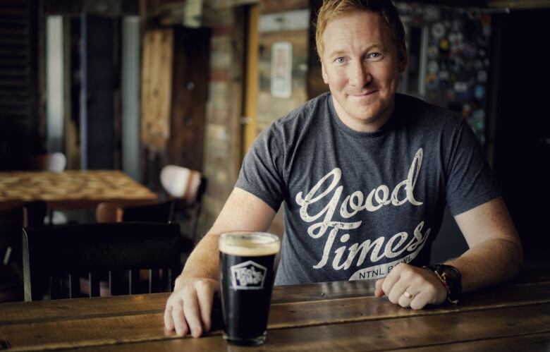 A man poses with a beer. 