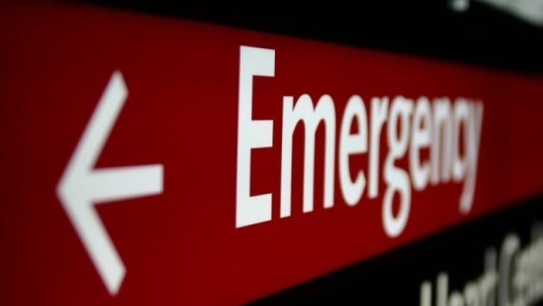 A close-up of a red sign with white lettering and an arrow pointing to a hospital emergency department.