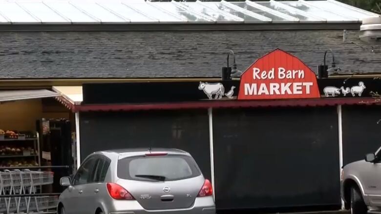 The exterior of grocery store Red Barn Market in Saanich with a red sign out front and shopping carts