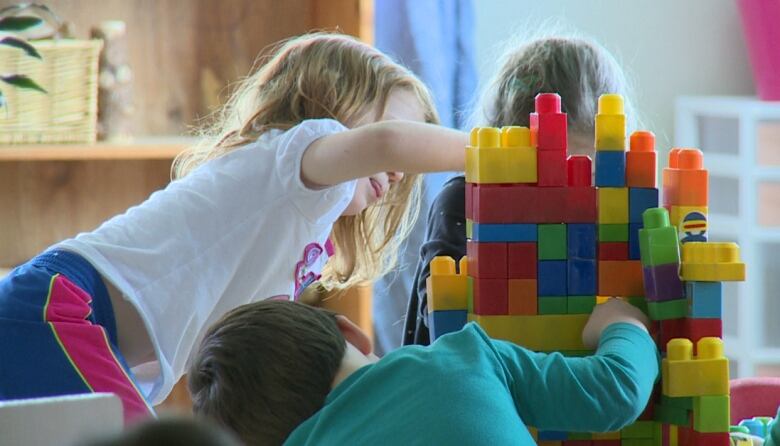 Three preschool kids play with colourful blocks.