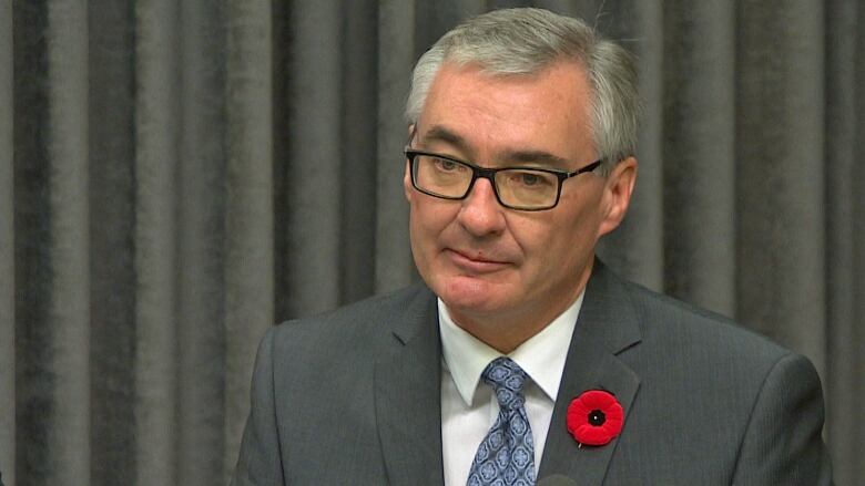 A portrait of a man in a suit with glasses.