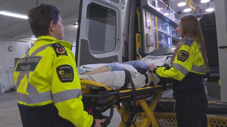 Paramedic lifting patient into ambulance.