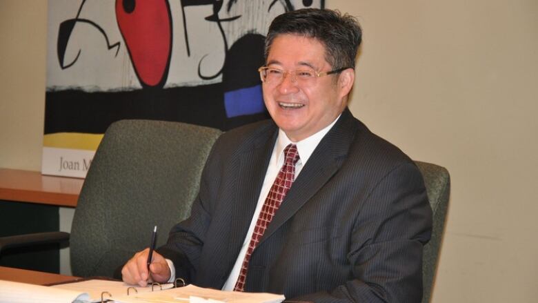 A man in a suit sitting at a board table.