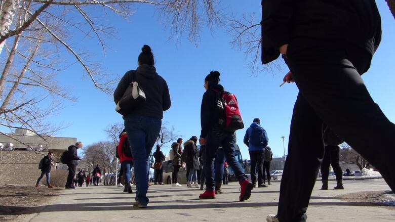 Dozens of students walking on a sidewalk