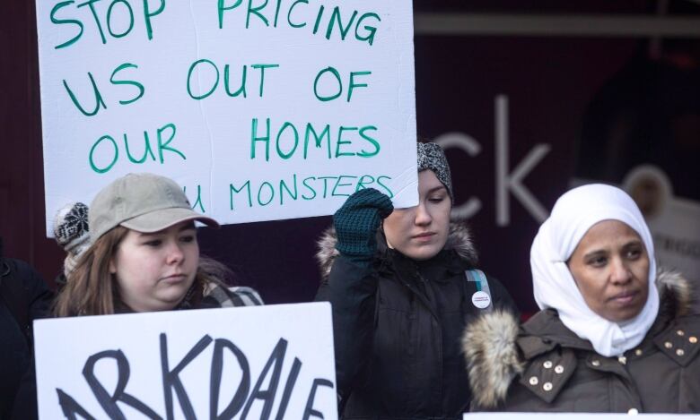 People hold up protest signs.