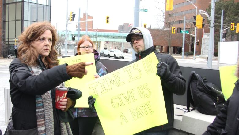 People hold yellow signs in protest - one sign reads 