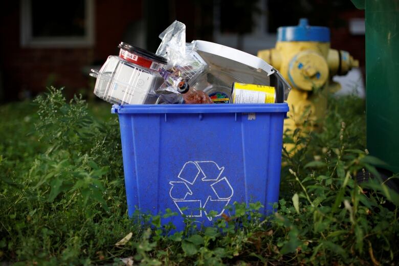 An overfilled recycling blue box. 