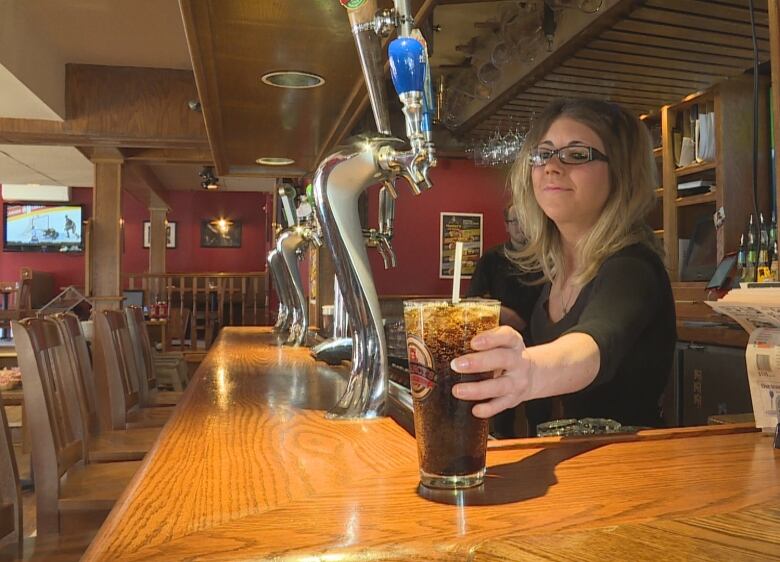 A bartender pushes an ice-filled drink down the bar.