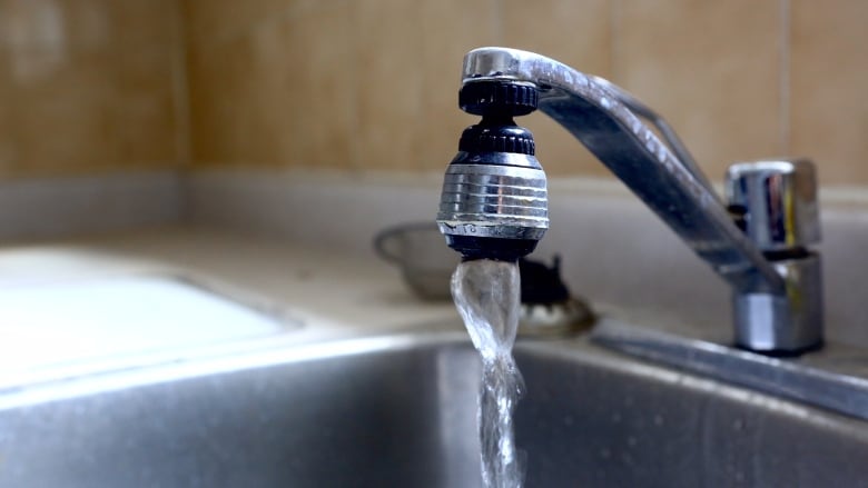 Water pours from a faucet over a sink.