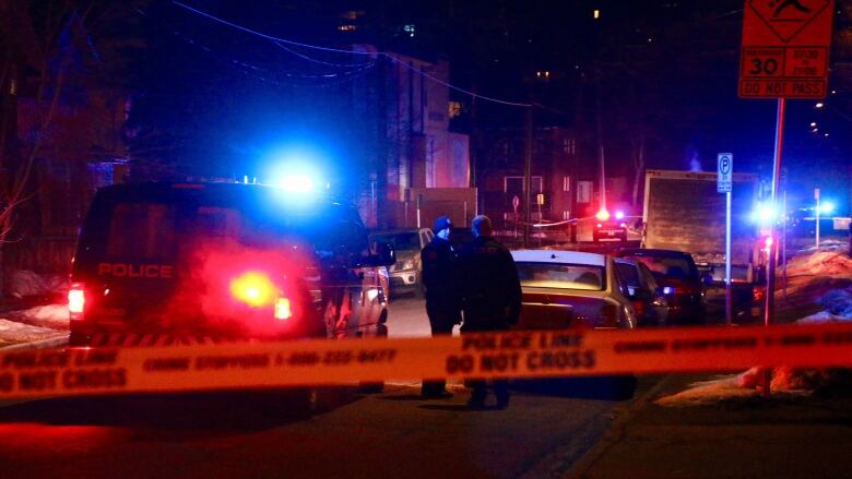 Night shot of a police crime scene with yellow tape and police cars. 