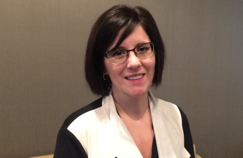 A woman wearing glasses and a black and white blouse.